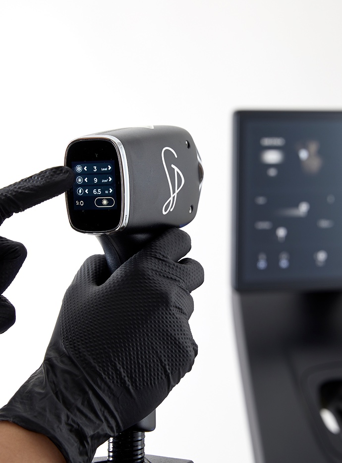 Practitioner adjusting the triple wavelength laser handpiece settings