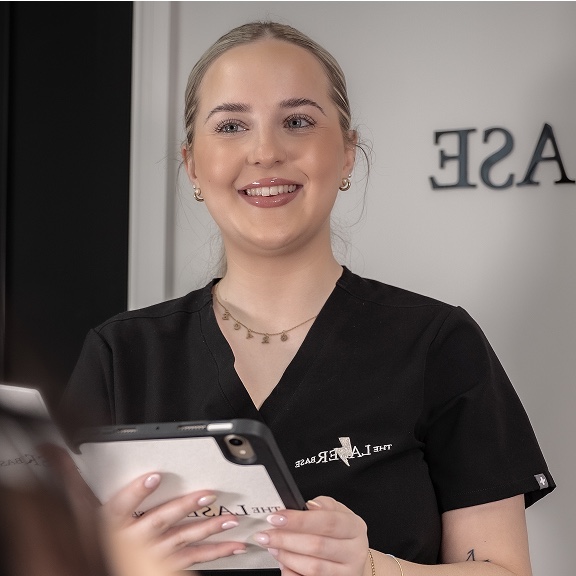 The Laser Base receptionist welcoming a client with a tablet