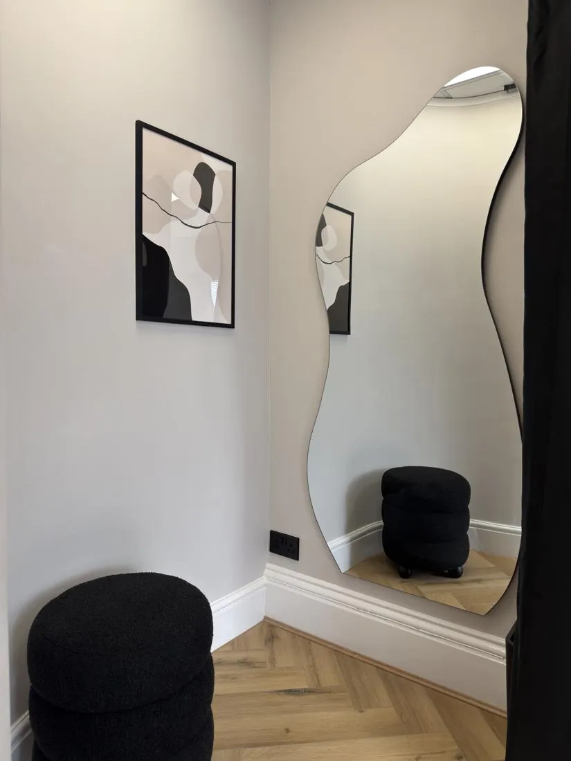 Private changing area with a full-length wavy mirror and seat