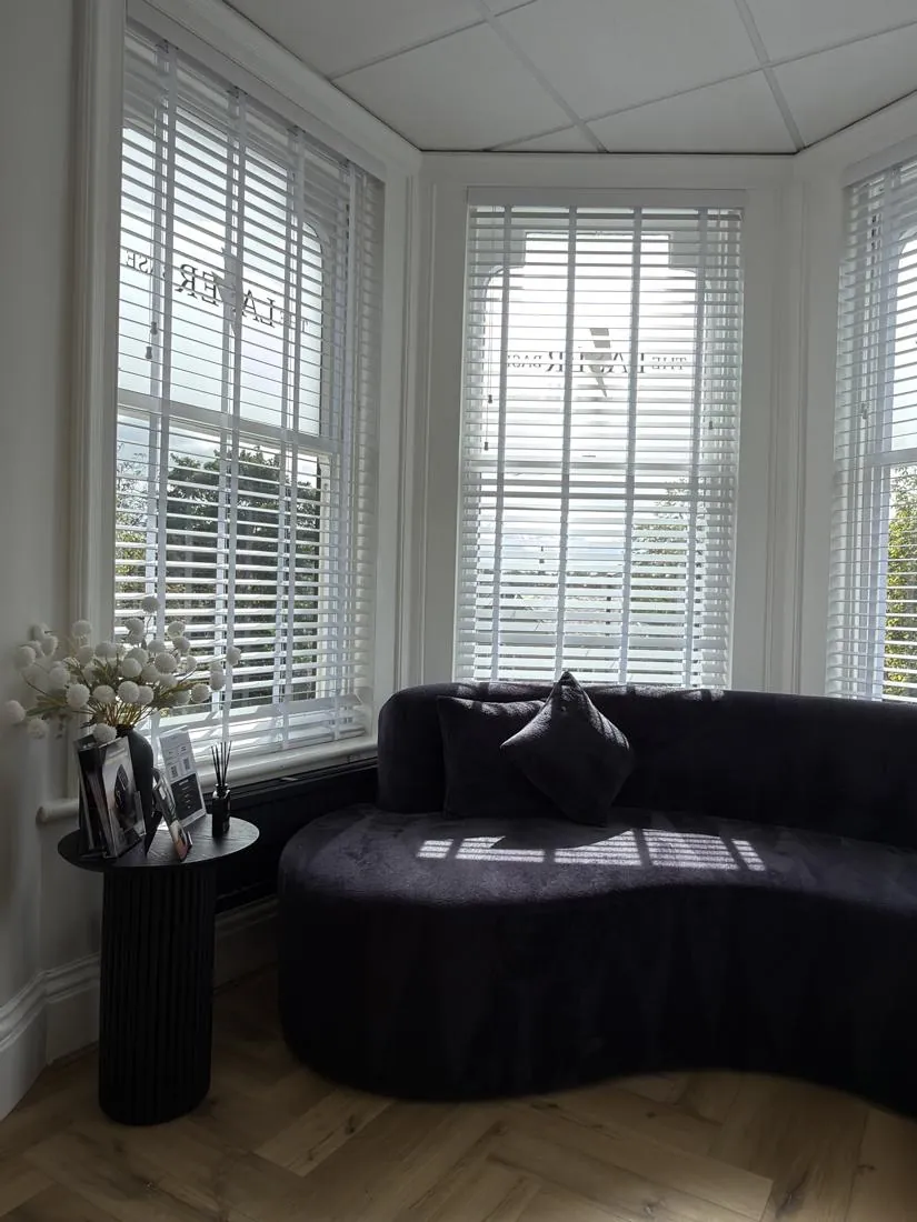 Waiting area with a curved sofa in a shuttered bay window