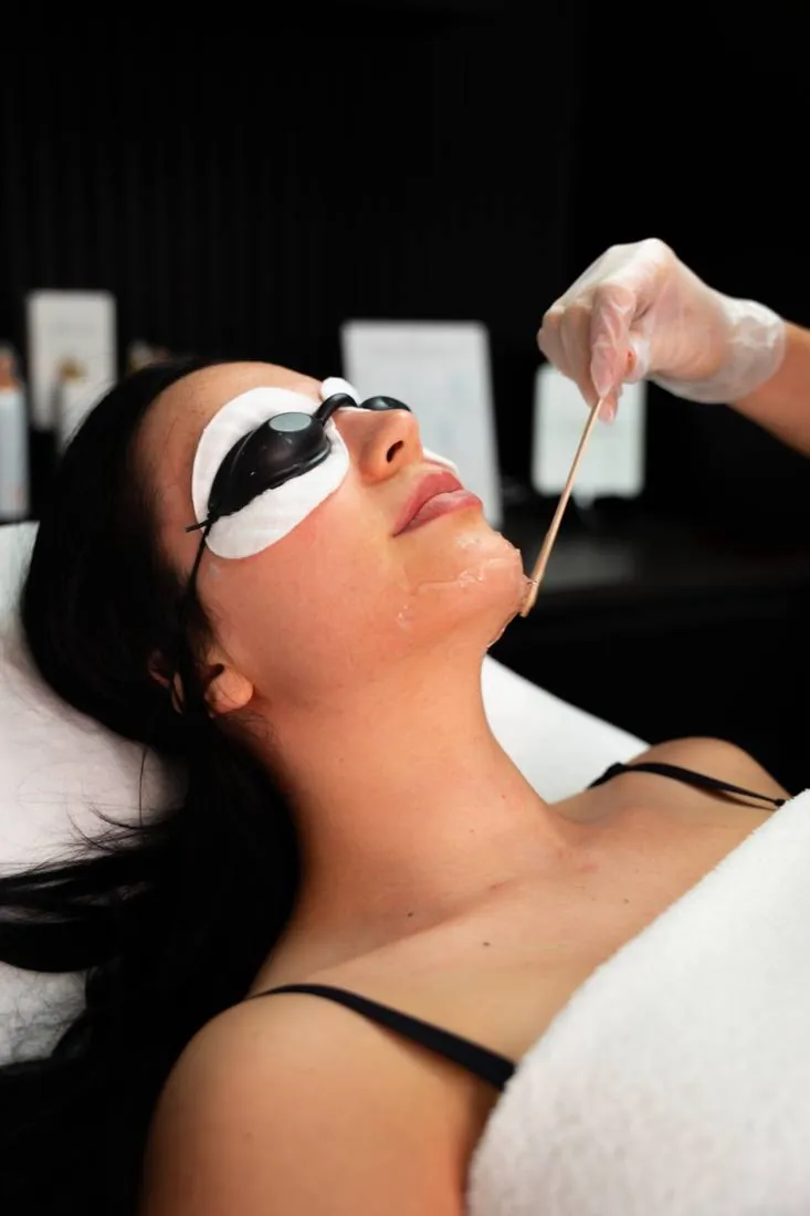 A client in protective eyewear having gel applied before a facial treatment