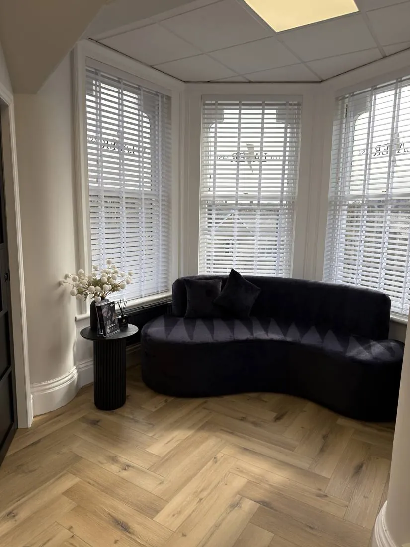 Client waiting area with a curved sofa in a shuttered bay window